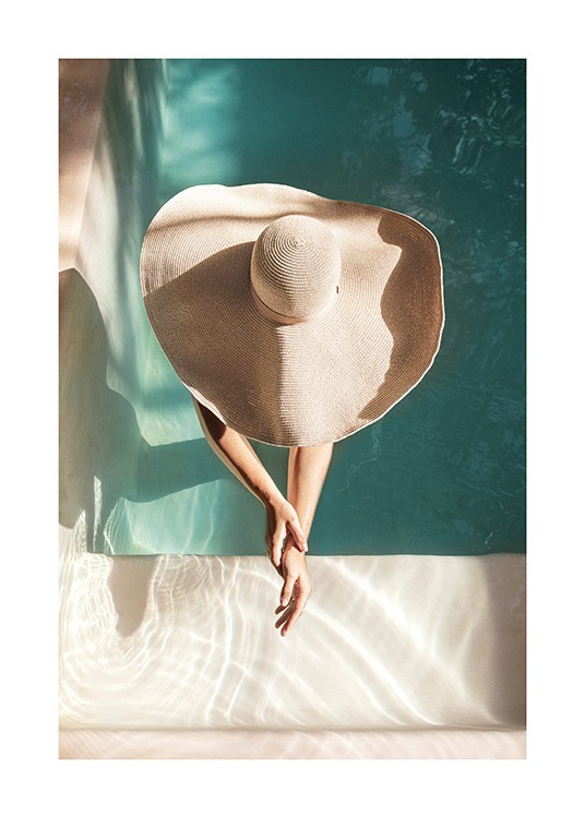  – Fotografia di una donna con un cappello da sole, in piedi in una piscina e con le braccia protese in avanti