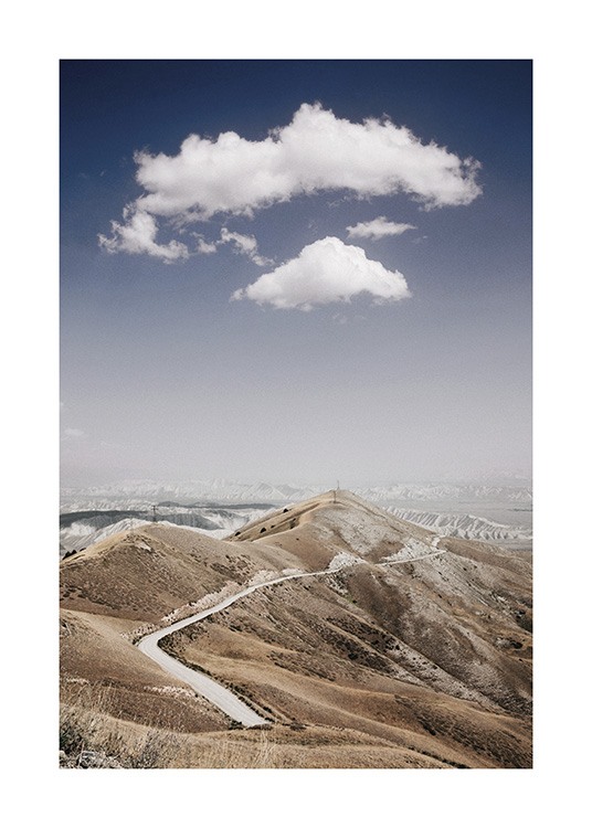 – Fotografia di una catena montuosa con una strada che la attraversa e nuvole e un cielo blu sullo sfondo