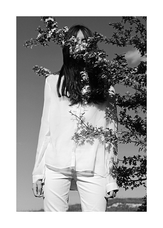  – Fotografia in bianco e nero di una donna che indossa un completo bianco con il ramo di un albero davanti al viso
