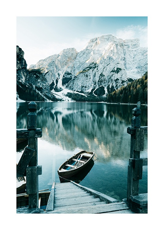  – Fotografia di montagne innevate ai confini di un lago con una barca e una scala in legno in primo piano