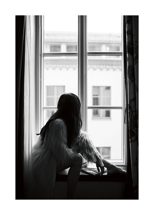  – Fotografia in bianco e nero di una donna con i capelli scuri seduta sul davanzale di una finestra con una giacca in ecopelliccia