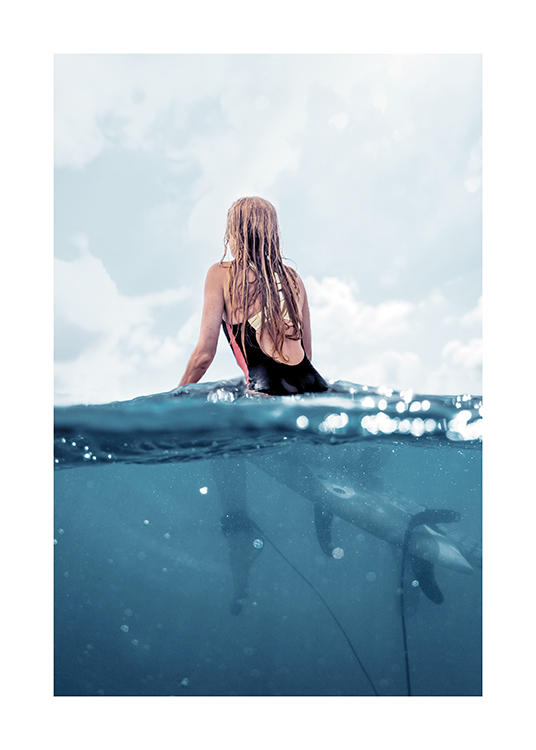  – Fotografia di una donna seduta su una tavola da surf nell'oceano, vista di spalle