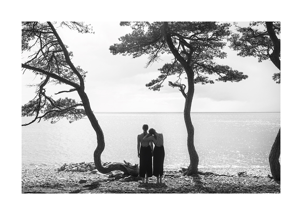  – Fotografia in bianco e nero di due donne che osservano il mare da una spiaggia con alberi