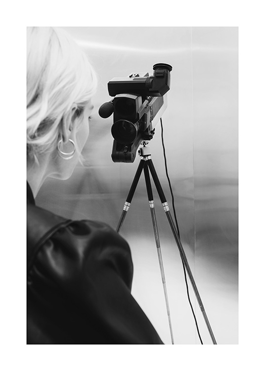  – Fotografia in bianco e nero di una donna con i capelli biondi dietro una videocamera