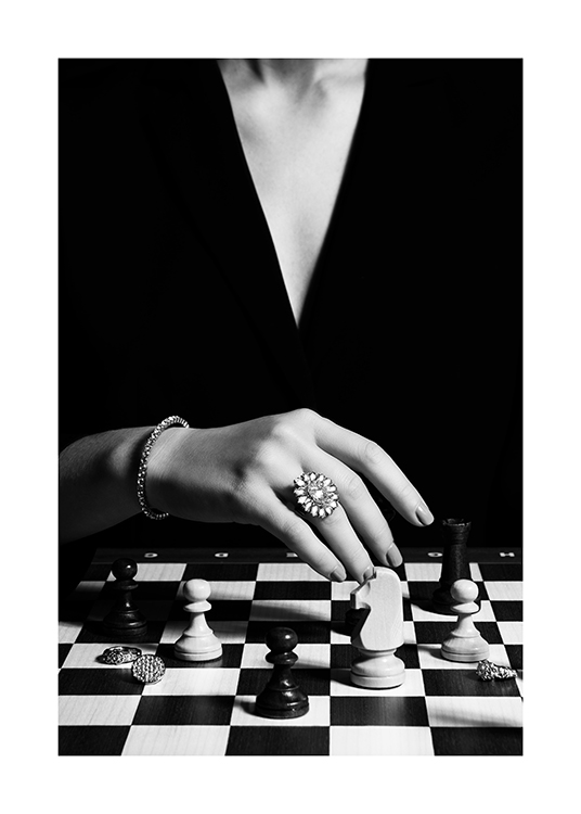 – Fotografia in bianco e nero di una donna che gioca a scacchi e indossa un grande anello al dito